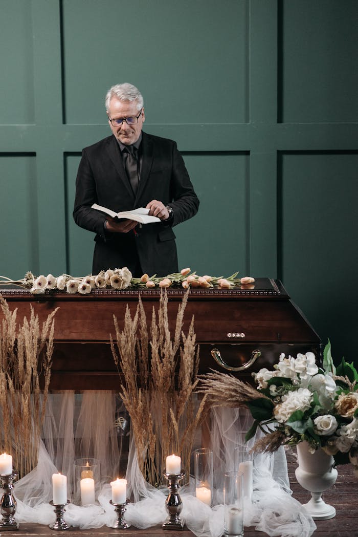 who-we-are A pastor presides over a funeral ceremony with a coffin surrounded by flowers and candles, creating a solemn atmosphere.